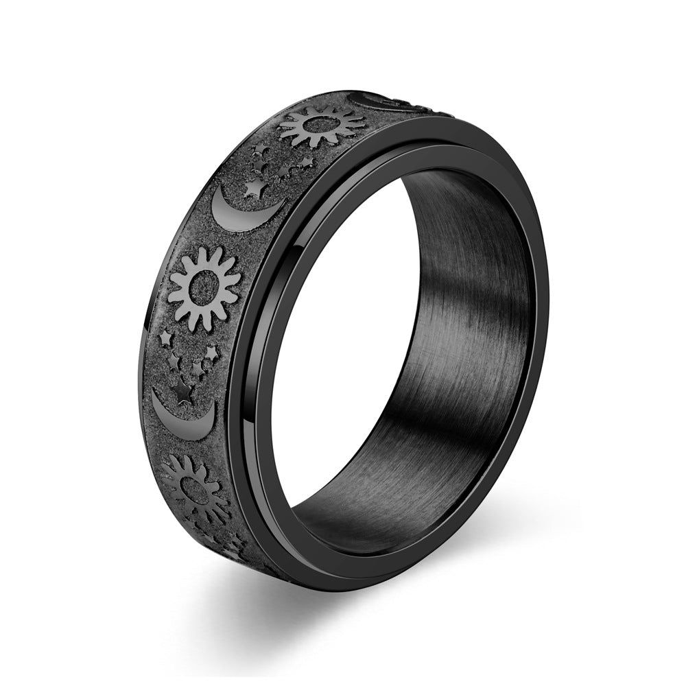 Black spinning ring with embossed sun star moon designs on a white background
