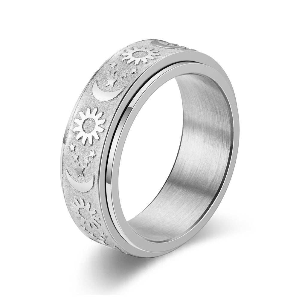 Silver coloured spinning ring with sun , stars and moon designs on a white background