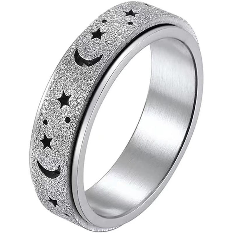Silver textured spinning ring with star and moon designs on a white background